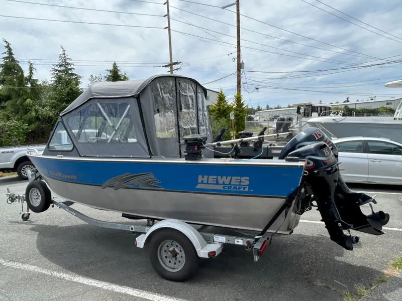 Slide: The Image of 1999 Hewescraft Sea Runner 179 boat on trailer, parked outdoors, with visible outboard motors. - 8