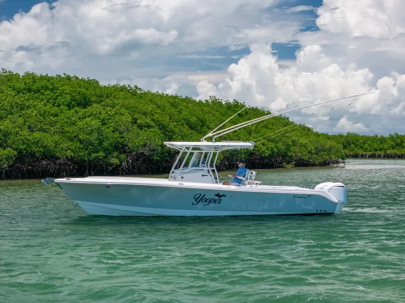 The Image of 2017 Edgewater 318CC boat cruising on a sunny day near lush green mangroves. - 1