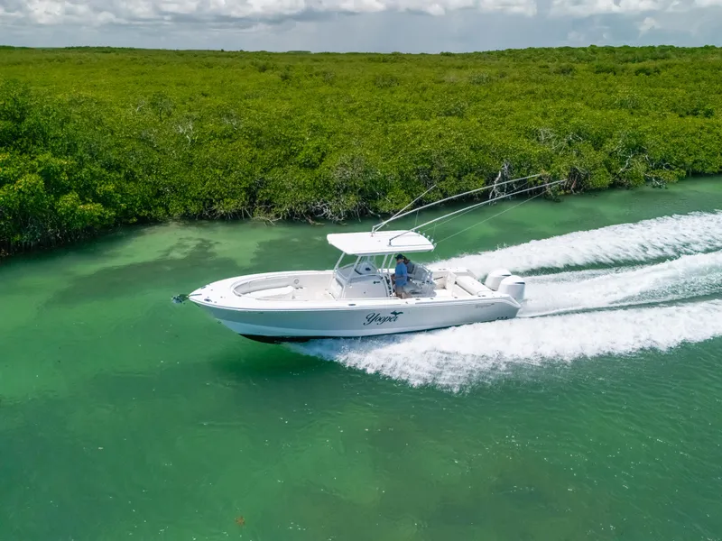 Slide: The Image of 2017 Edgewater 318CC boat cruising on clear turquoise water near lush green mangroves. - 15