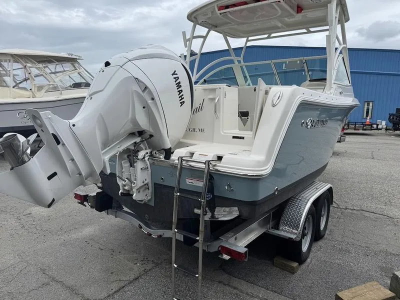 Slide: The Image of 2023 Sailfish 245 DC boat with Yamaha engine on trailer, parked outdoors. - 2