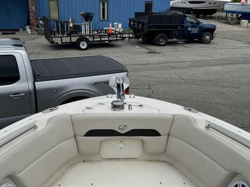 Slide: The Image of 2023 Sailfish 245 DC boat interior with parked trucks in the background. - 5