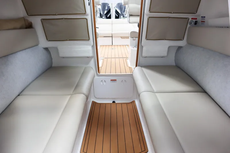 Slide: The Image of Interior of 2025 Protector 310 Targa boat with beige seating and wood flooring. - 13