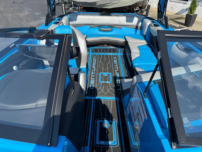 Slide: The Image of 2022 Centurion Fi23 boat interior with blue and gray seating, open windshield, and branded flooring. - 12