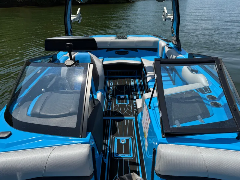 Slide: The Image of 2022 Centurion Fi23 boat interior with blue and gray seating on a calm lake. - 17