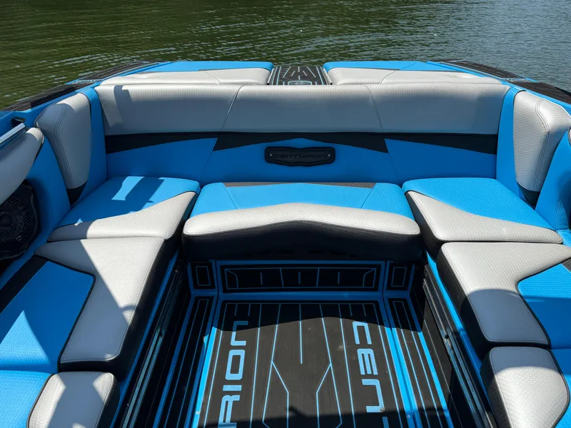 Slide: The Image of 2022 Centurion Fi23 boat interior with blue and gray seating, on calm water. - 19
