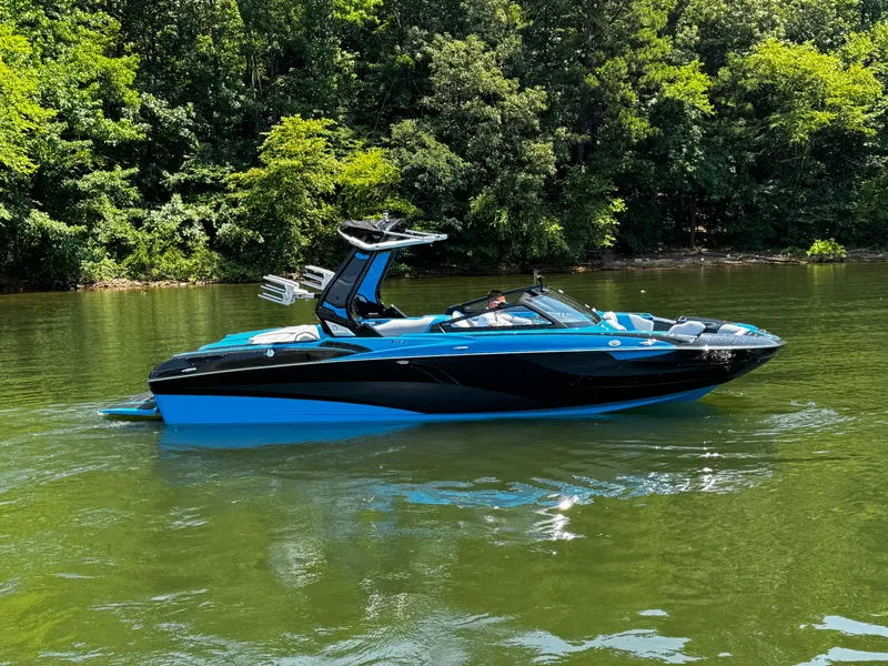Slide: The Image of 2022 Centurion Fi23 boat on a calm lake with lush green forest background. - 2
