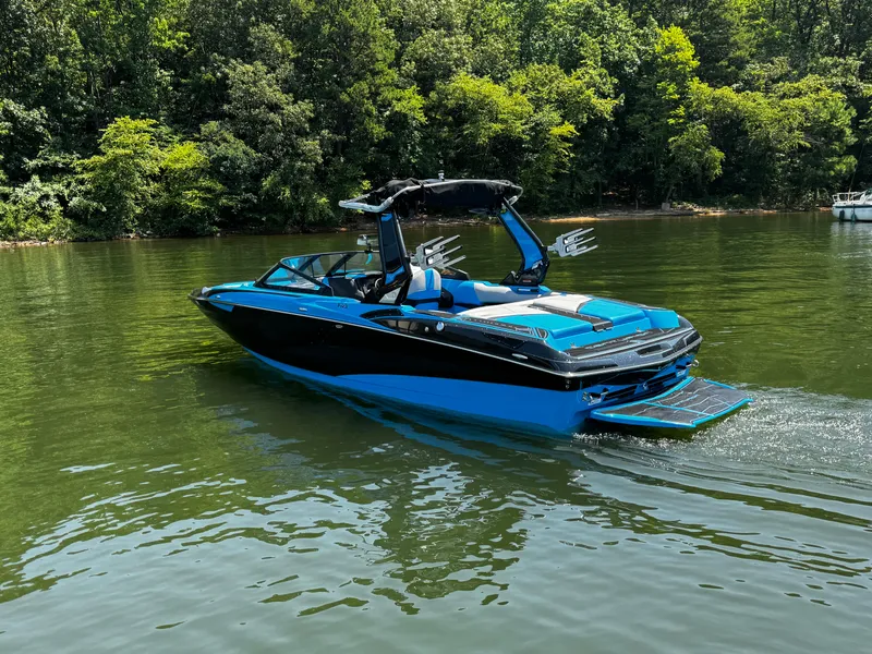 Slide: The Image of 2022 Centurion Fi23 boat in blue and black on a calm lake, surrounded by trees. - 4