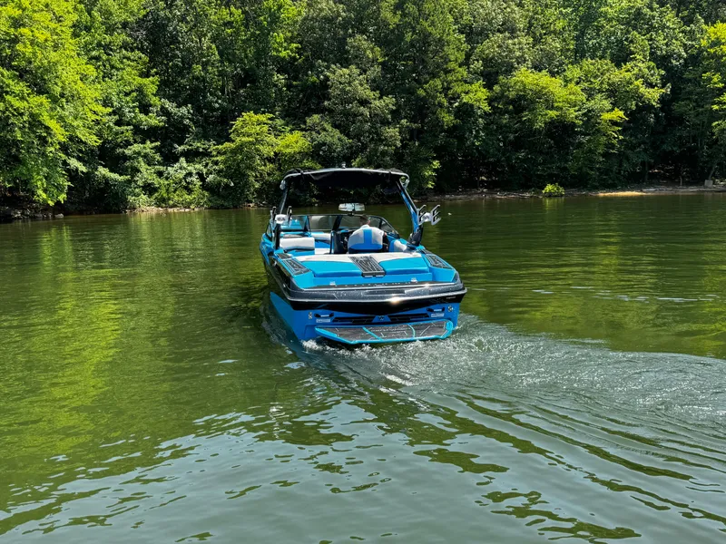 Slide: The Image of 2022 Centurion Fi23 boat on a serene lake surrounded by lush greenery. - 5