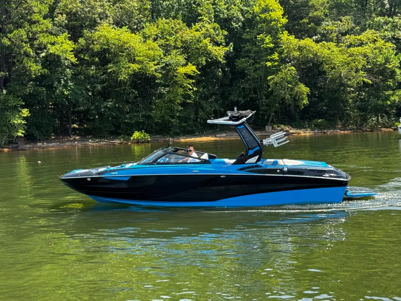 Slide: The Image of 2022 Centurion Fi23 boat cruising on a serene lake with lush green trees. - 6