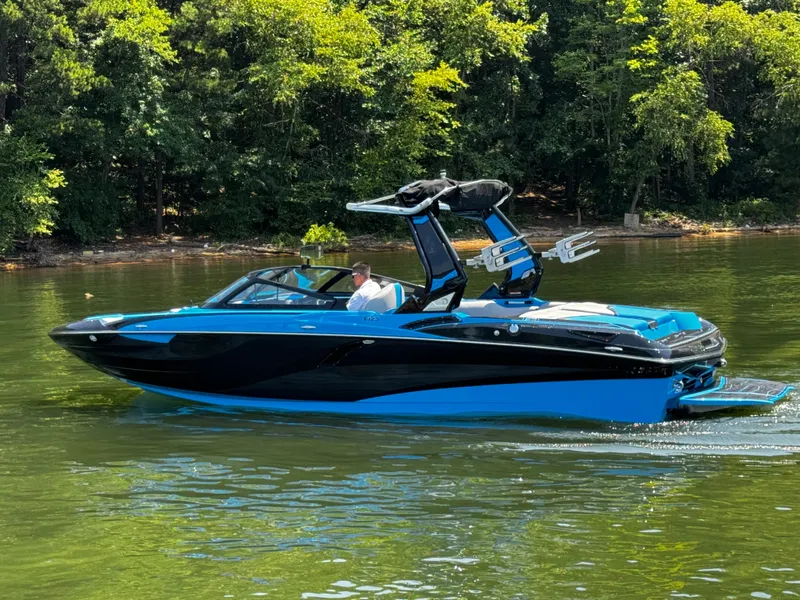 Slide: The Image of 2022 Centurion Fi23 boat cruising on a serene lake with lush green forest backdrop. - 7