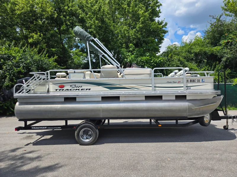Slide: The Image of 2006 Sun Tracker FISHIN' BARGE 21 pontoon boat on trailer, surrounded by lush greenery. - 9