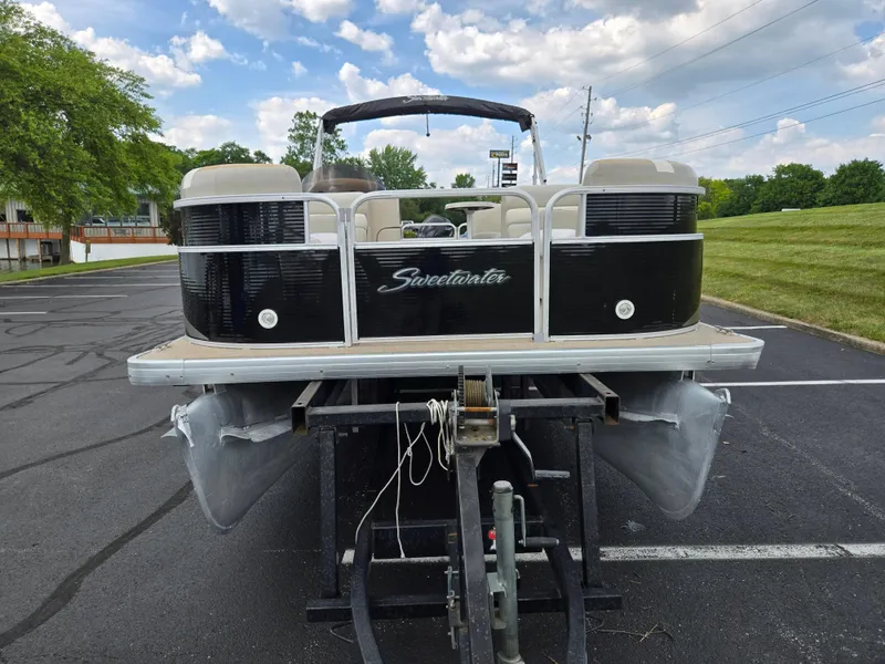 Slide: The Image of 2012 Sweetwater 2486 pontoon boat on trailer, parked on asphalt, with grassy background. - 6