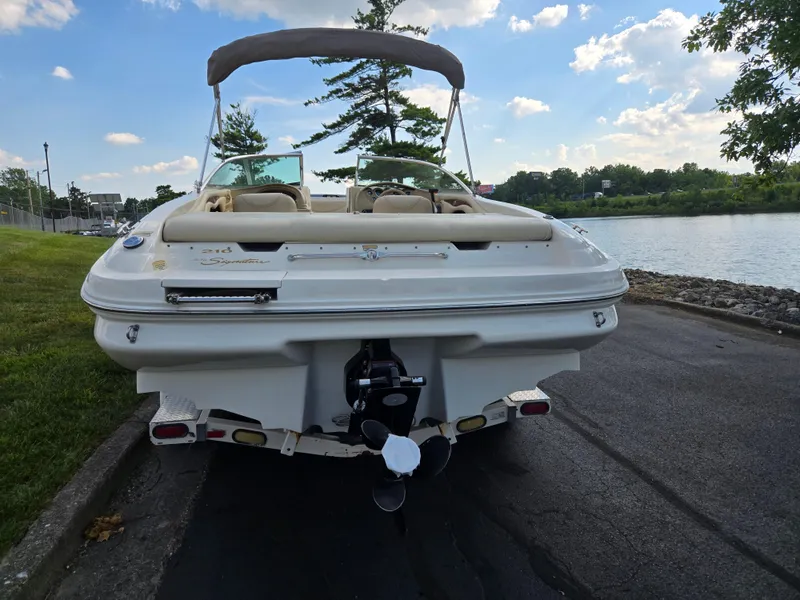 Slide: The Image of 1999 Sea Ray 210 BR boat parked by a scenic lakeside under a blue sky. - 2