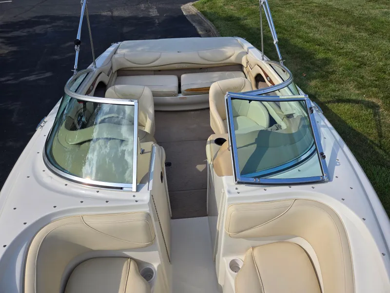 Slide: The Image of 1999 Sea Ray 210 BR boat interior with beige seating and windshield, parked on grass. - 22