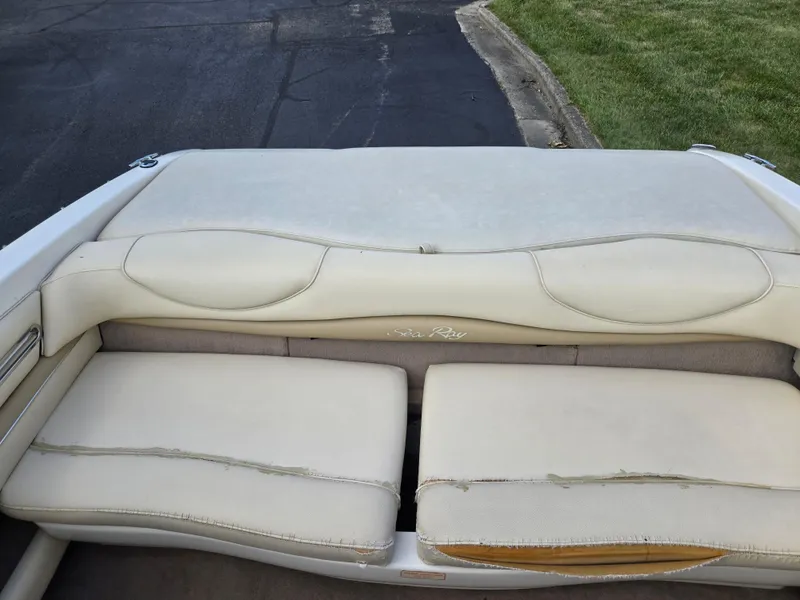 Slide: The Image of 1999 Sea Ray 210 BR boat interior with worn beige seating and visible stitching. - 24