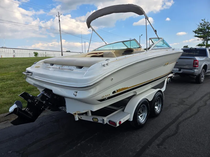 Slide: The Image of 1999 Sea Ray 210 BR boat on trailer, parked near a truck under a blue sky. - 3