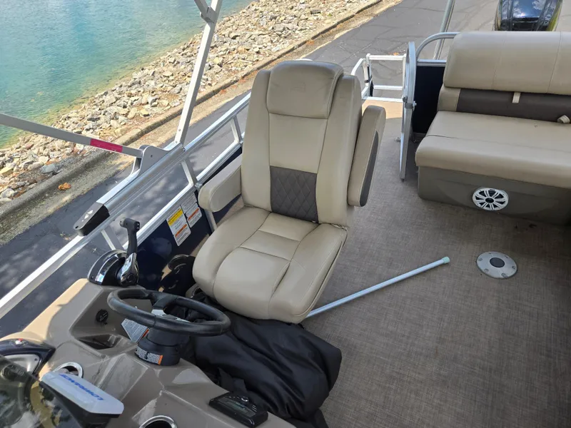 Slide: The Image of 2022 Sun Tracker Party Barge 20 DLX interior with beige seating and steering wheel. - 15