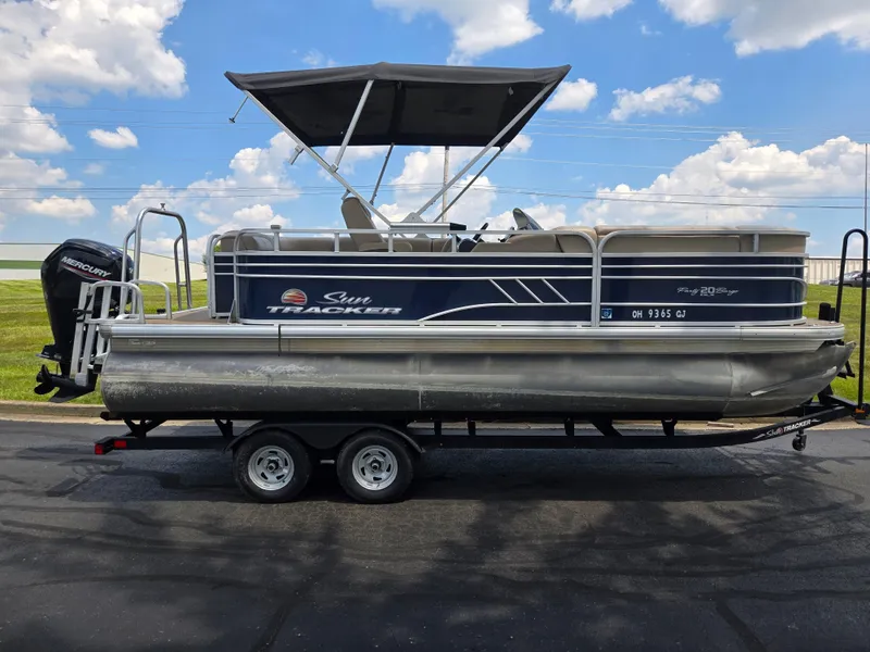 Slide: The Image of 2022 Sun Tracker Party Barge 20 DLX pontoon boat on trailer, under blue sky. - 4