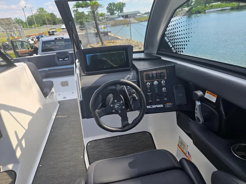 Slide: The Image of 2021 Scarab 285 ID boat interior with steering wheel and control panel by the water. - 16