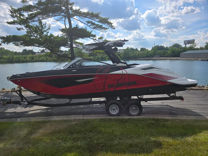 Slide: The Image of 2021 Scarab 285 ID boat on trailer by a lake, under a blue sky. - 9
