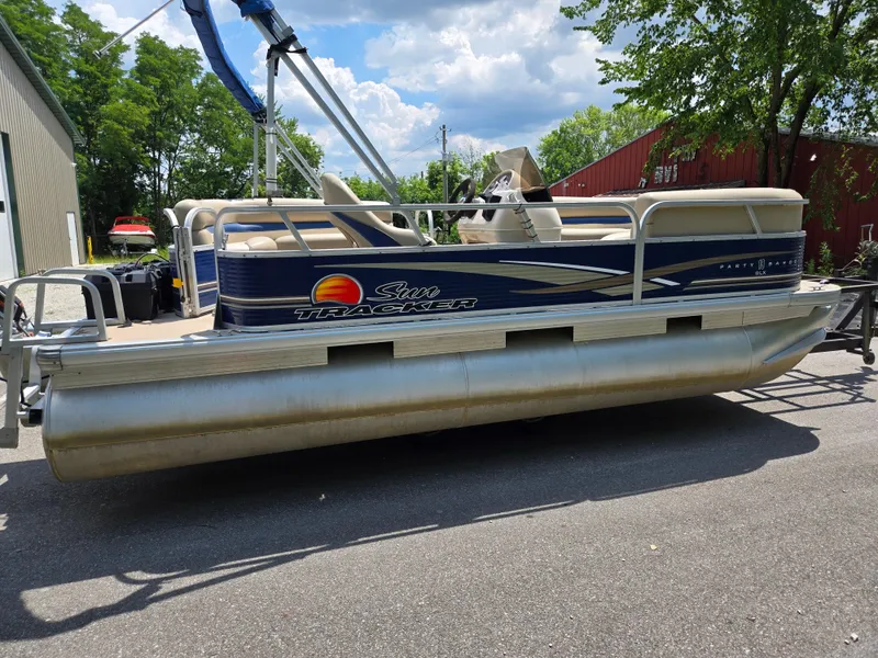Slide: The Image of 2013 Sun Tracker Party Barge 18 DLX pontoon boat on trailer, parked outdoors. - 4