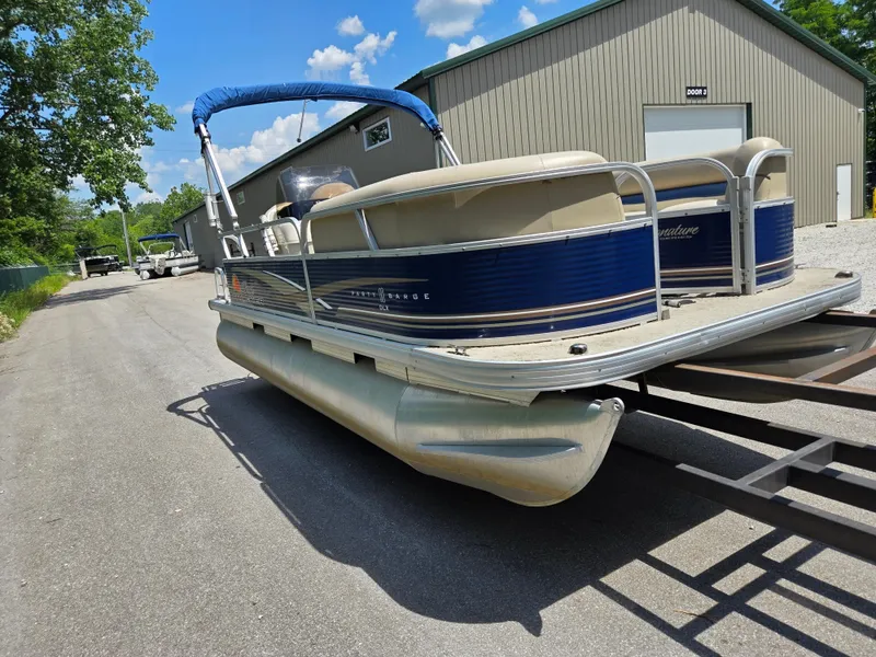 Slide: The Image of 2013 Sun Tracker Party Barge 18 DLX pontoon boat on trailer, parked near a building. - 5