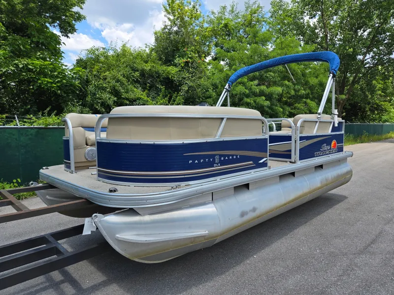 Slide: The Image of 2013 Sun Tracker Party Barge 18 DLX pontoon boat on trailer, surrounded by greenery. - 8