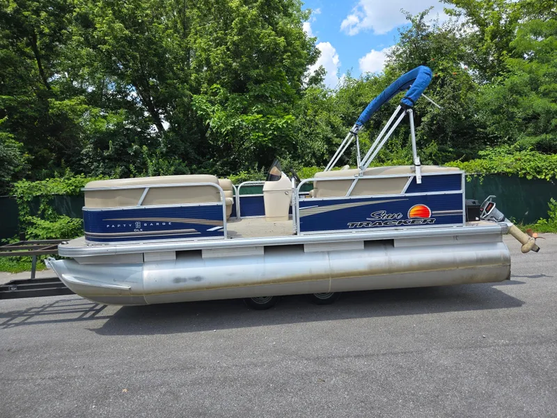 Slide: The Image of 2013 Sun Tracker Party Barge 18 DLX pontoon boat on trailer, surrounded by lush greenery. - 9