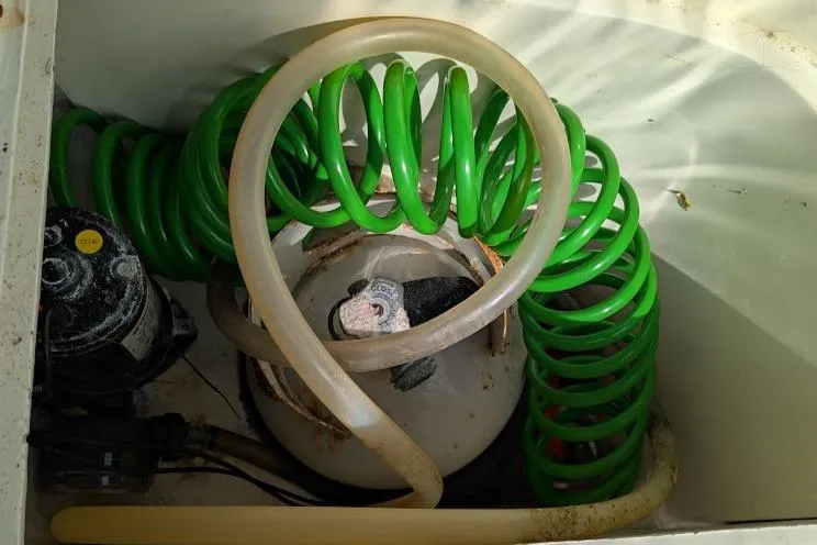 Slide: The Image of Coiled green hose and propane tank in Newport 326, 1995 model compartment. - 22