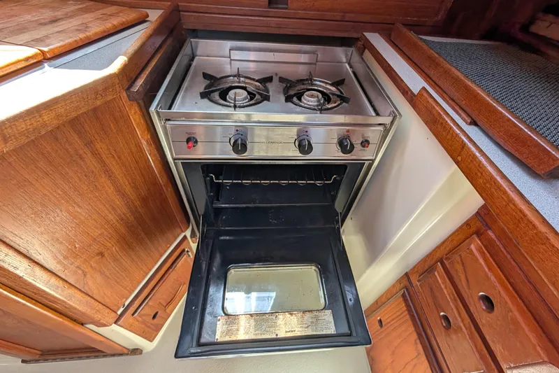 Slide: The Image of 1995 Newport 326 kitchen with open oven and dual-burner stove, surrounded by wooden cabinetry. - 25
