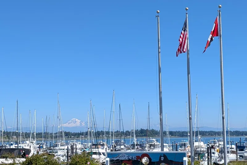 Slide: The Image of Marina with sailboats, flags, and distant mountain under clear blue sky. Newport 326, 1995. - 36