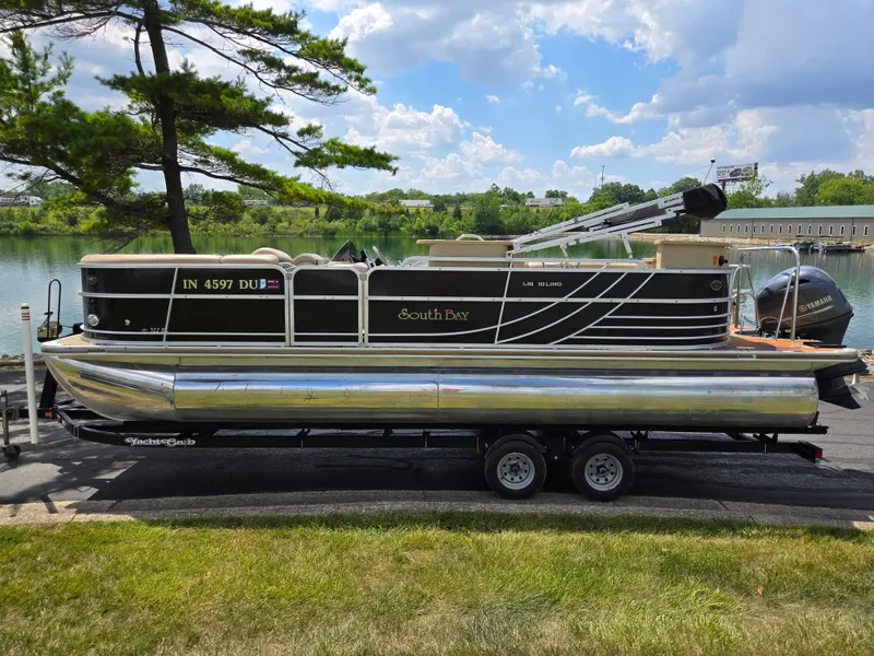Slide: The Image of 2014 South Bay 522 E pontoon boat on trailer by a lake, under a blue sky. - 9