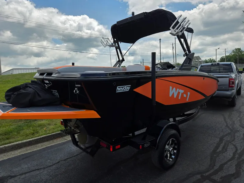 Slide: The Image of 2016 Heyday WT-1 boat on trailer, featuring orange and black design under cloudy sky. - 3