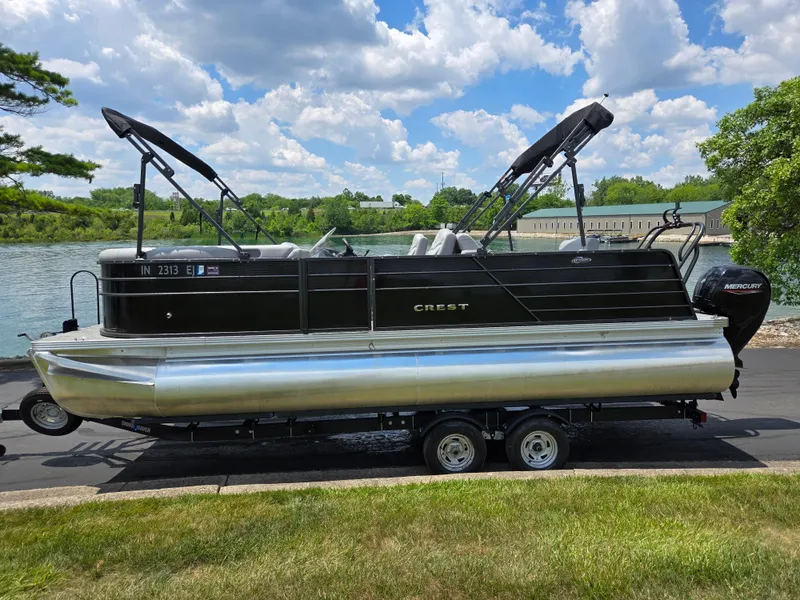 Slide: The Image of 2022 Crest Classic DLX 220 pontoon boat on trailer by a scenic lake. - 10