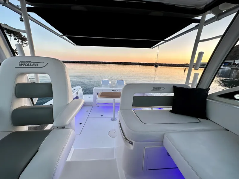 Slide: The Image of 2014 Boston Whaler 315 Conquest boat interior at sunset, featuring comfortable seating and scenic water view. - 11