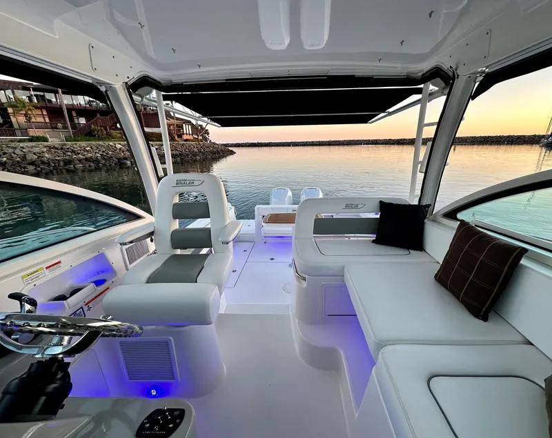 Slide: The Image of 2014 Boston Whaler 315 Conquest interior with seating, steering wheel, and waterfront view. - 12