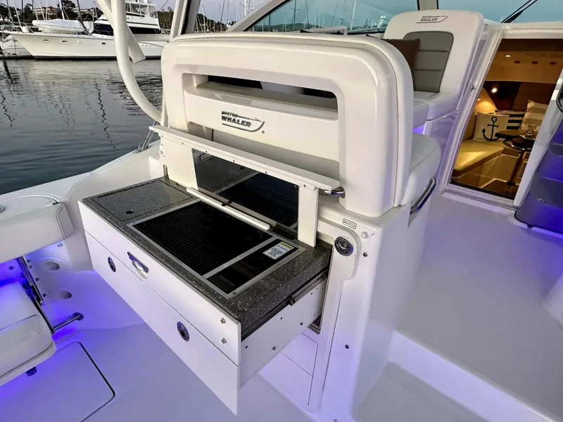 Slide: The Image of 2014 Boston Whaler 315 Conquest boat interior with grill and seating area. - 14
