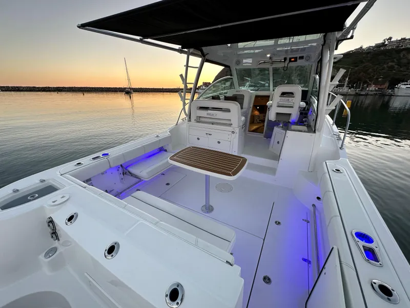Slide: The Image of 2014 Boston Whaler 315 Conquest boat interior at sunset, featuring seating and ambient lighting. - 15