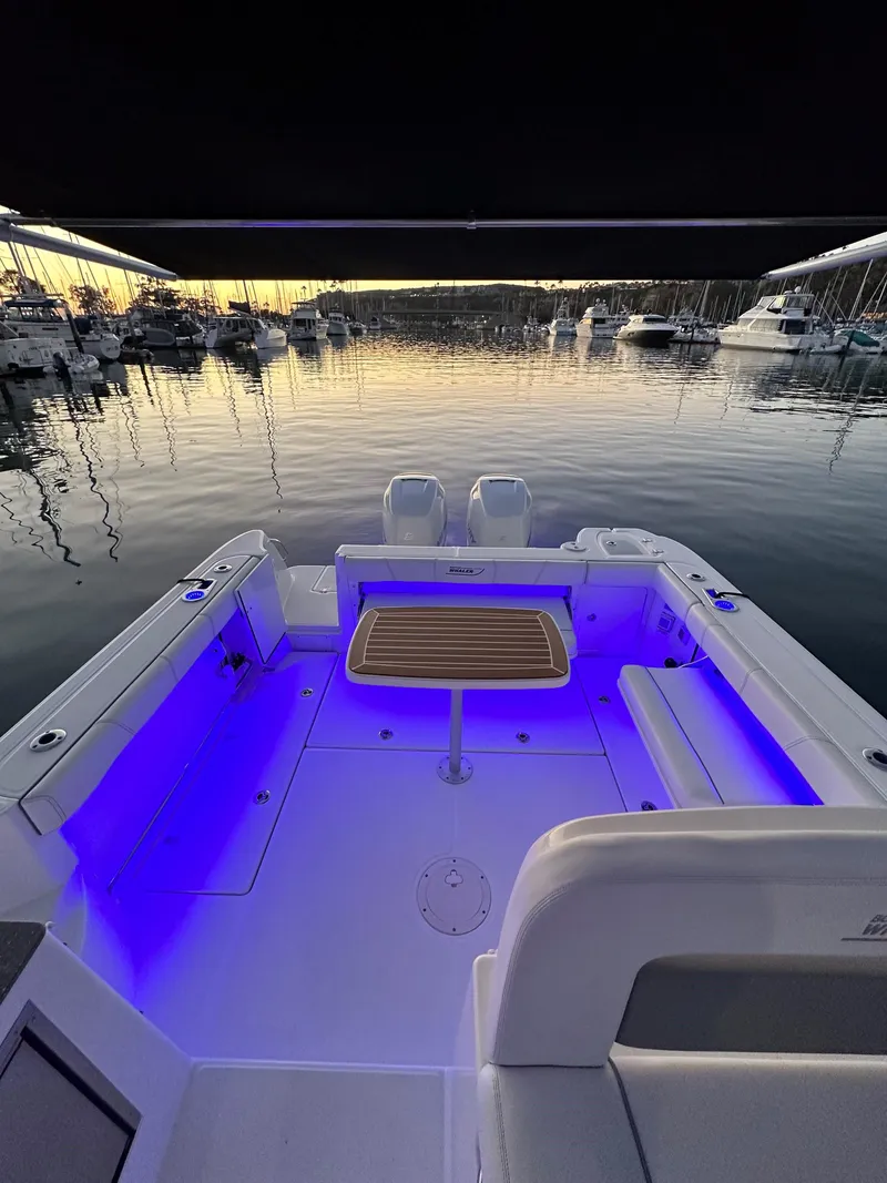 Slide: The Image of 2014 Boston Whaler 315 Conquest boat with blue LED lights at sunset in a marina. - 20