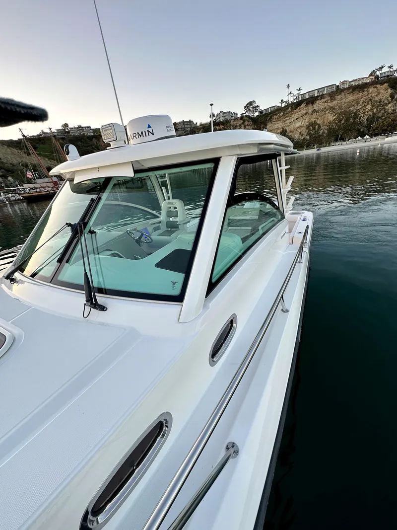 Slide: The Image of 2014 Boston Whaler 315 Conquest boat docked in a serene harbor setting. - 31