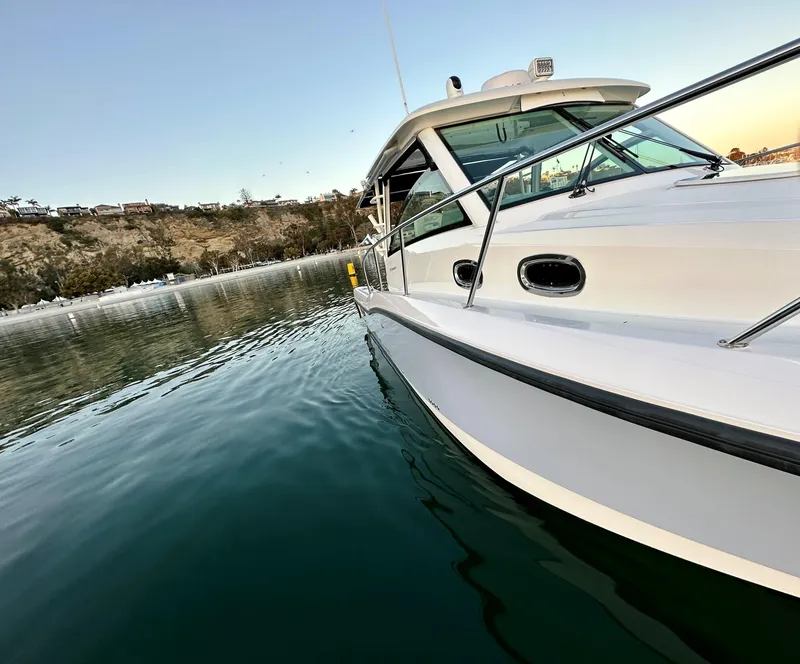 Slide: The Image of 2014 Boston Whaler 315 Conquest boat on calm water, scenic coastal background. - 32