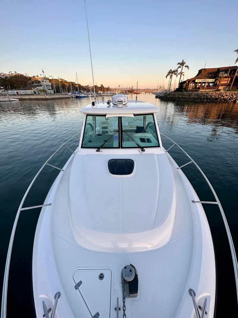 Slide: The Image of 2014 Boston Whaler 315 Conquest boat docked in a serene marina at sunset. - 34