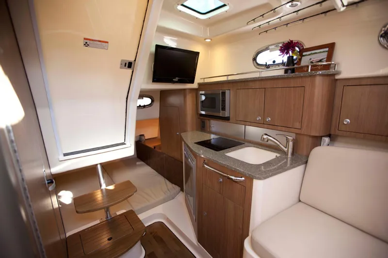 Slide: The Image of Manufacturer Provided Image: 2014 Boston Whaler 315 Conquest cabin interior with kitchenette, seating, and TV. - 47