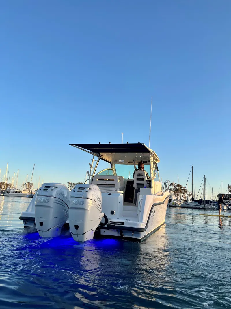 Slide: The Image of 2014 Boston Whaler 315 Conquest boat with dual engines, illuminated in blue, docked at marina. - 7