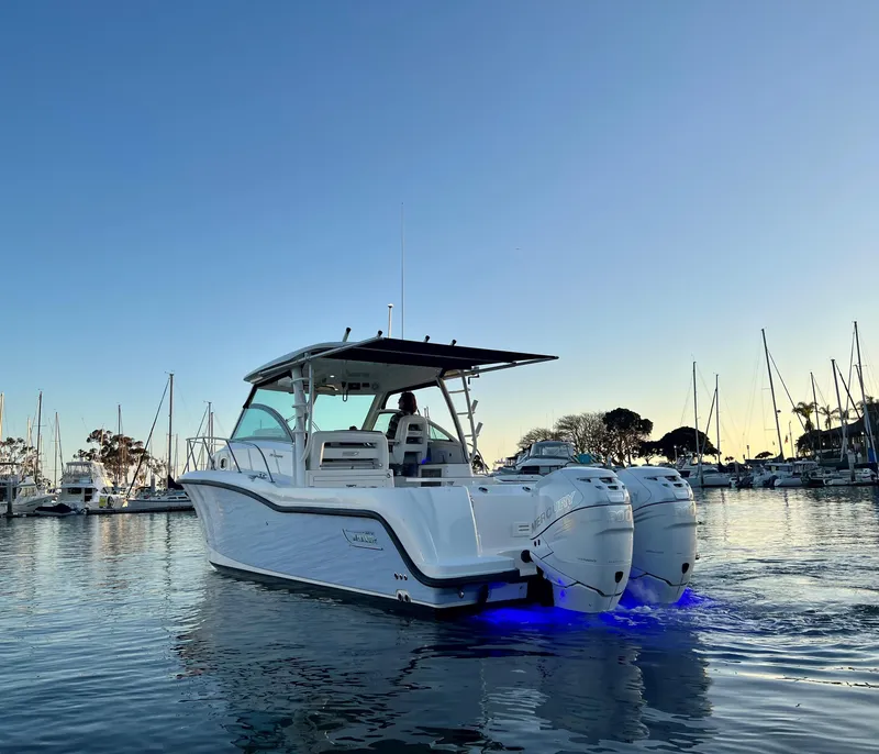 Slide: The Image of 2014 Boston Whaler 315 Conquest boat in marina at sunset with blue underwater lights. - 8