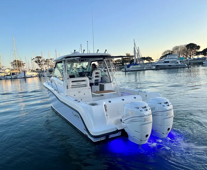 Slide: The Image of 2014 Boston Whaler 315 Conquest boat with dual Mercury engines in a marina at sunset. - 9