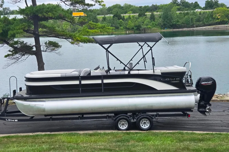Slide: The Image of 2022 Lowe SS 230 CL pontoon boat on trailer by a lake. - 0