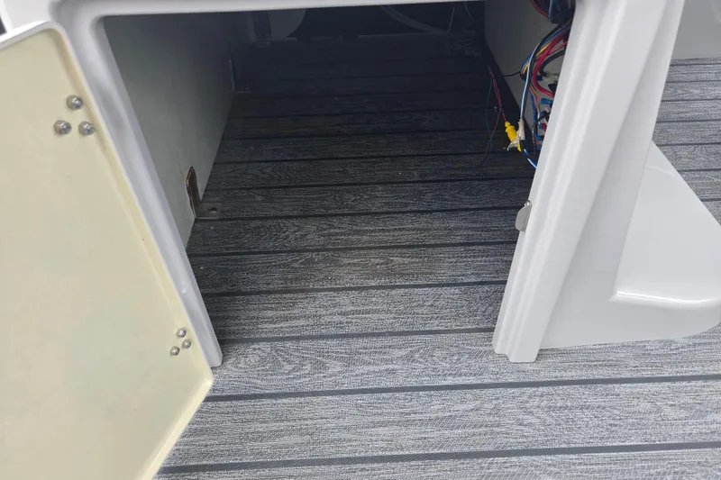 Slide: The Image of Open storage compartment with wiring inside a 2022 Lowe SS 230 CL boat. - 14
