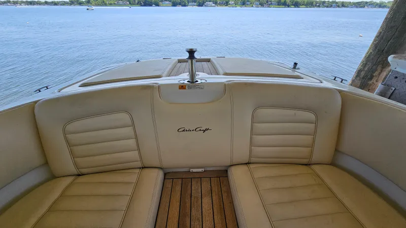 Slide: The Image of 2013 Chris-Craft Launch 22 boat interior with beige seating and wooden deck, overlooking calm water. - 15