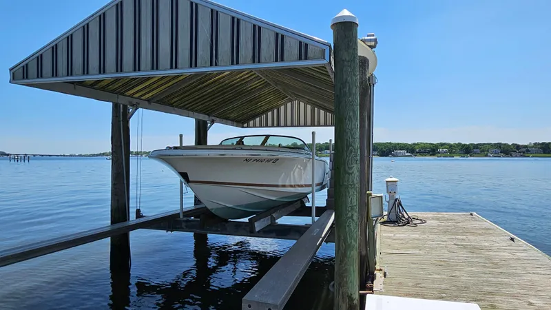 Slide: The Image of 2013 Chris-Craft Launch 22 boat on lift at dockside, under a striped canopy. - 2